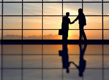 Business People shake hands at airport sunset