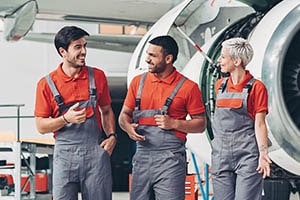 Three aerospace workers having a discussion in front of a aeroplane engine