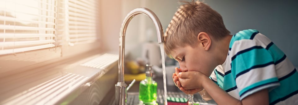 child drinking water from a tap, highlighting it's safe and passes regulations