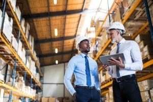 Two men in a warehouse auditing