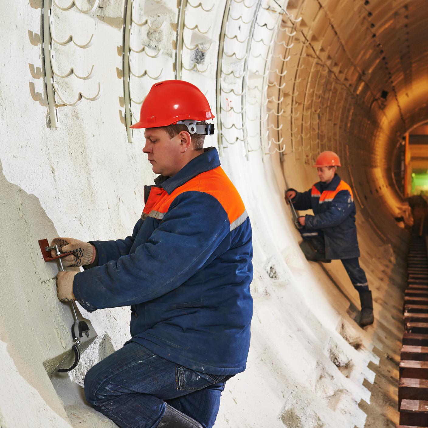 Tunneller worker installing fixture in underground subway metro construction site