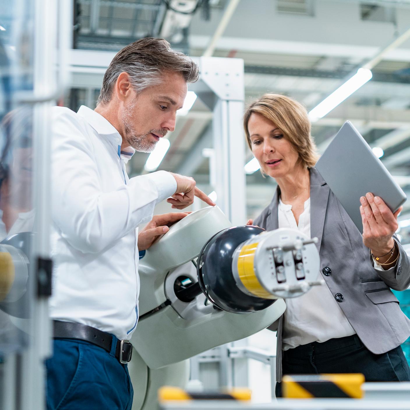 Businesswoman and man talking at assembly robot in a factory