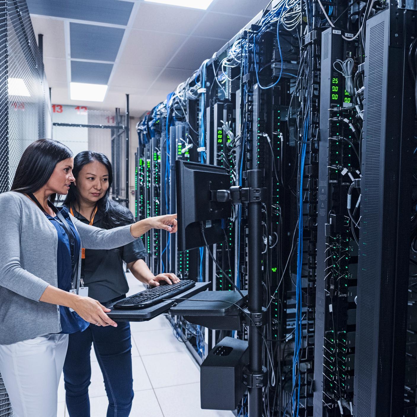 Two women working with computer in server room