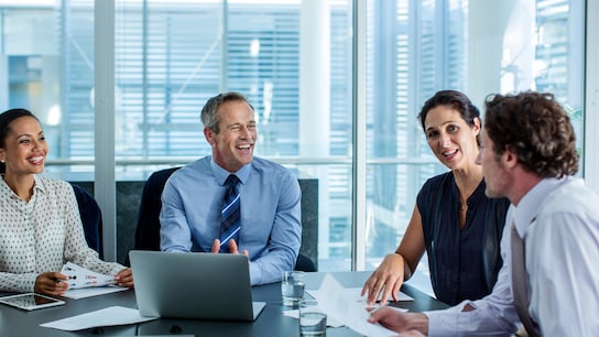 Happy business professionals discussing at conference table in office