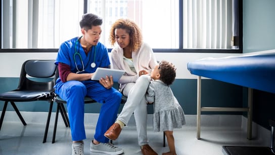 Krankenpfleger zeigt der Mutter eines Kleinkindes im Krankenhaus ein digitales Tablet