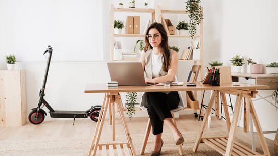 Businesswoman using laptop at desk in office.