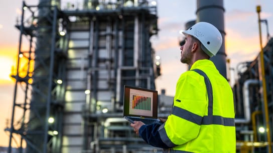 Industrial Engineer Monitoring Facility with Technology During Sunset.