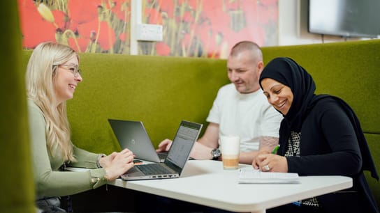 Coworkers seated at a table and working togheter with their laptop