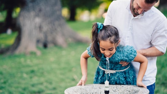 Junger Vater und seine Tochter trinken Wasser