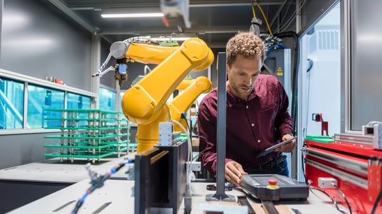 Businessman checking industrial robot in high tech company.