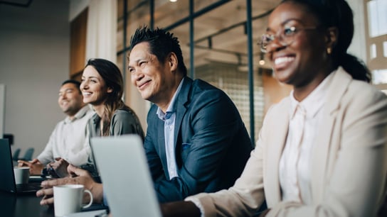 Des collègues souriants d’origines ethniques diverses discutent lors d’une réunion au bureau