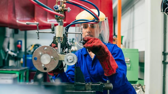 A young woman is using engineering equipment in a workshop