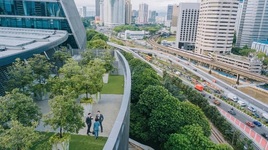 Three business person talking on roof top garden outside office building