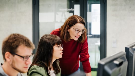 Eine Lehrerin hilft einer Studentin während eines Seminars an der Universität bei ihren Computeraufgaben.