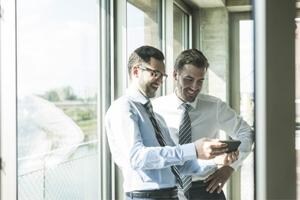 Two men examine a document onscreen