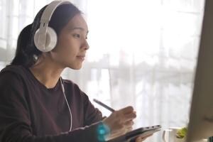 A woman looking at a computer with headphones on
