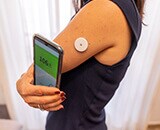 A woman using a mobile phone to check a wearable smart device