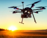 Drone flying in foreground with sunset in background.