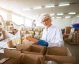 Woman checking contents of box in food industry warehouse.