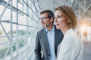 A man and woman looking out the window of a modern looking building