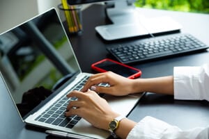 female hand typing on keyboard of laptop