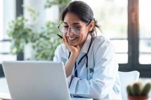 Female doctor sitting in front of a laptop looking at the screen