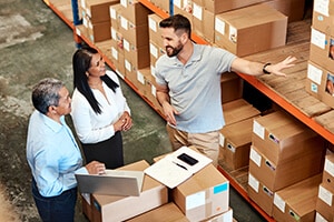 Three people in a warehouse inspecting goods