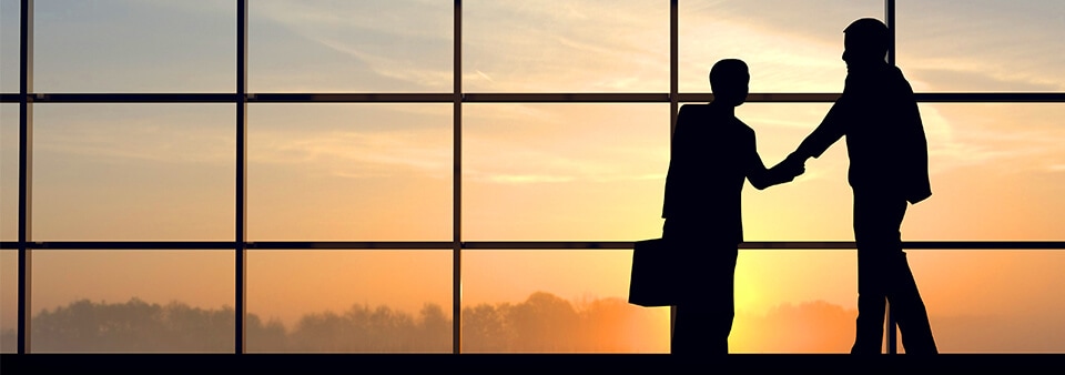 Business People shake hands at airport sunset