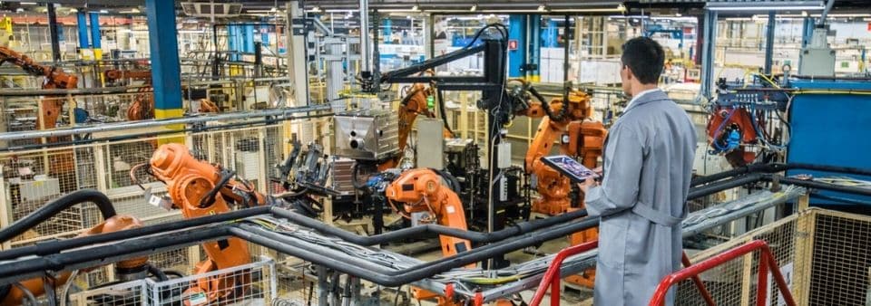 Robots in factory with workers observing them