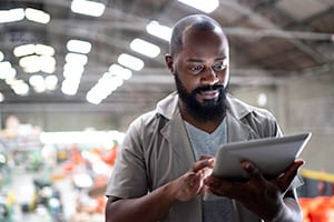 A man in a warehouse looks at a tablet