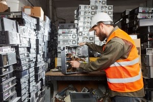 A man wearing PPE refurbishing electronics