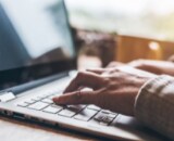 A person's hands typing on a laptop