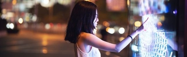 Young girl in city touching a digital screen