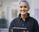 Woman working in food industry wearing protective overalls and hygiene hair net.