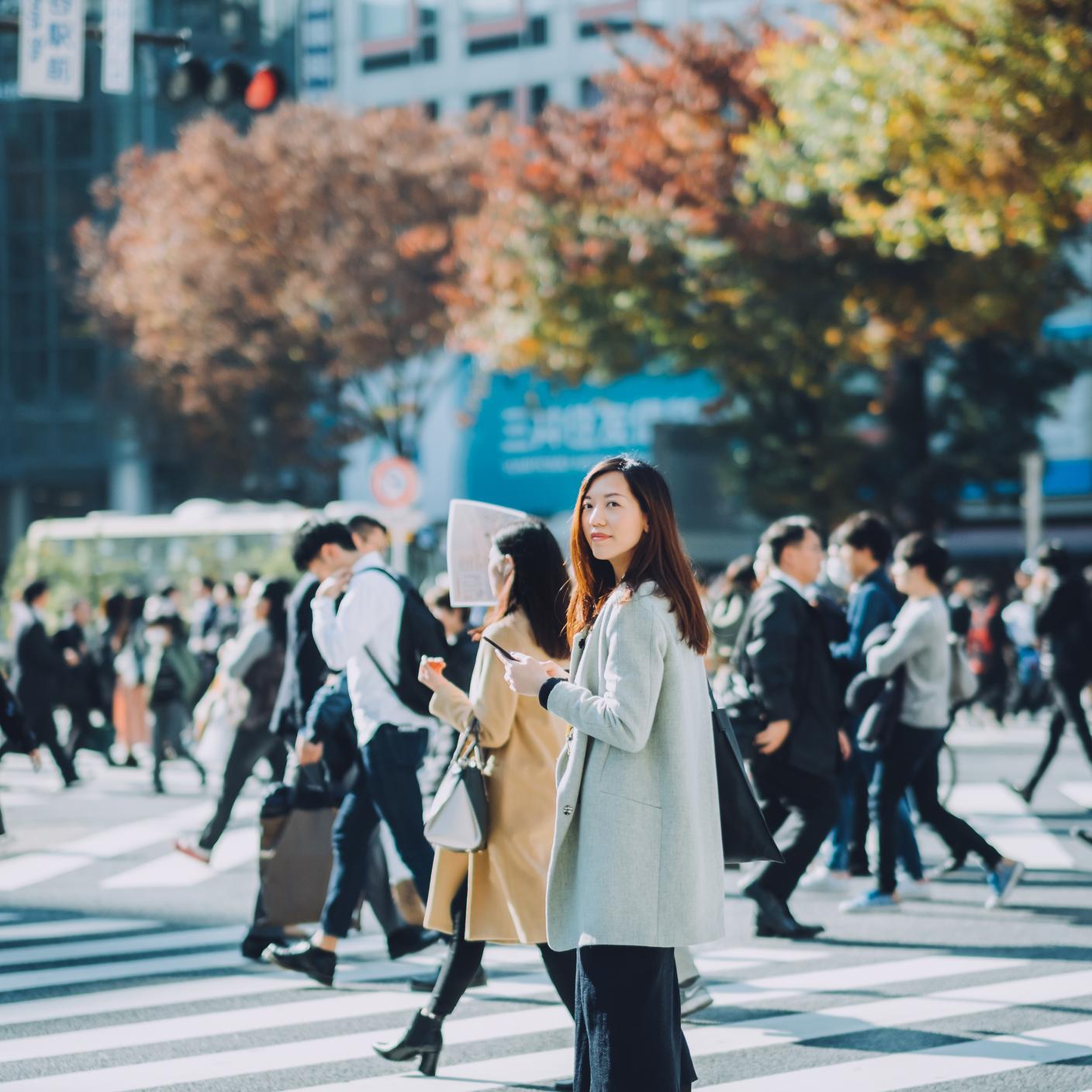 woman on mobile in city with trees and buildings