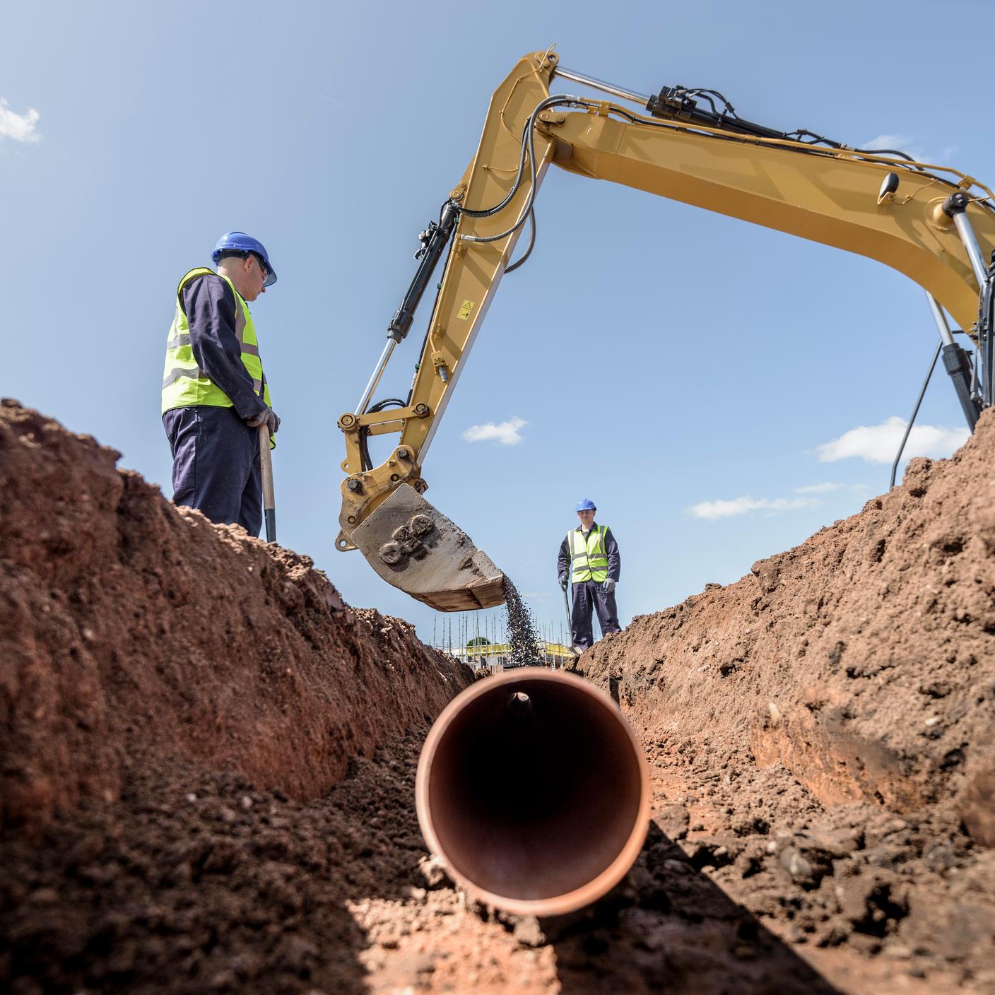 Builders laying pipework on housing building site