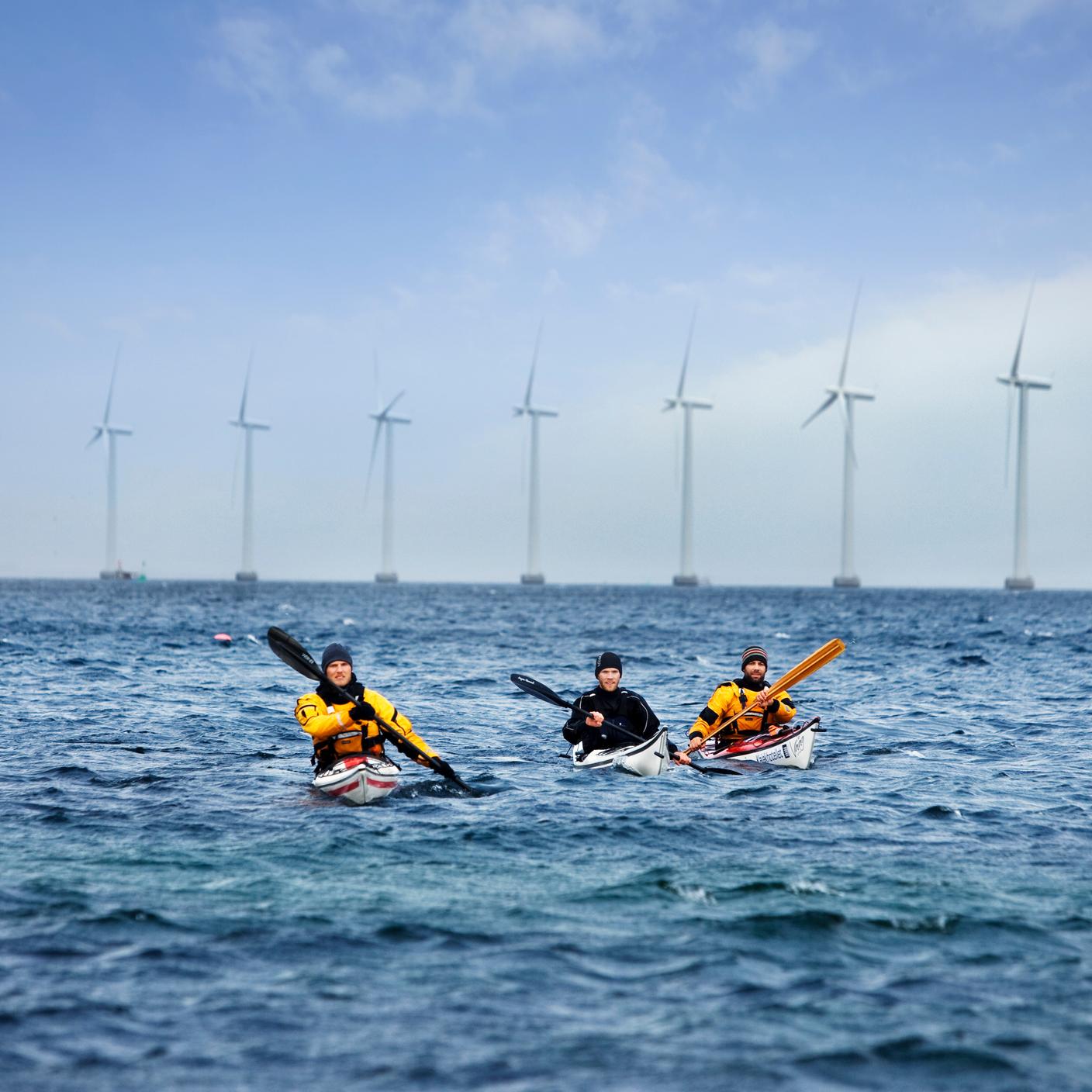 Kayaks at sea in front of wind turbines
