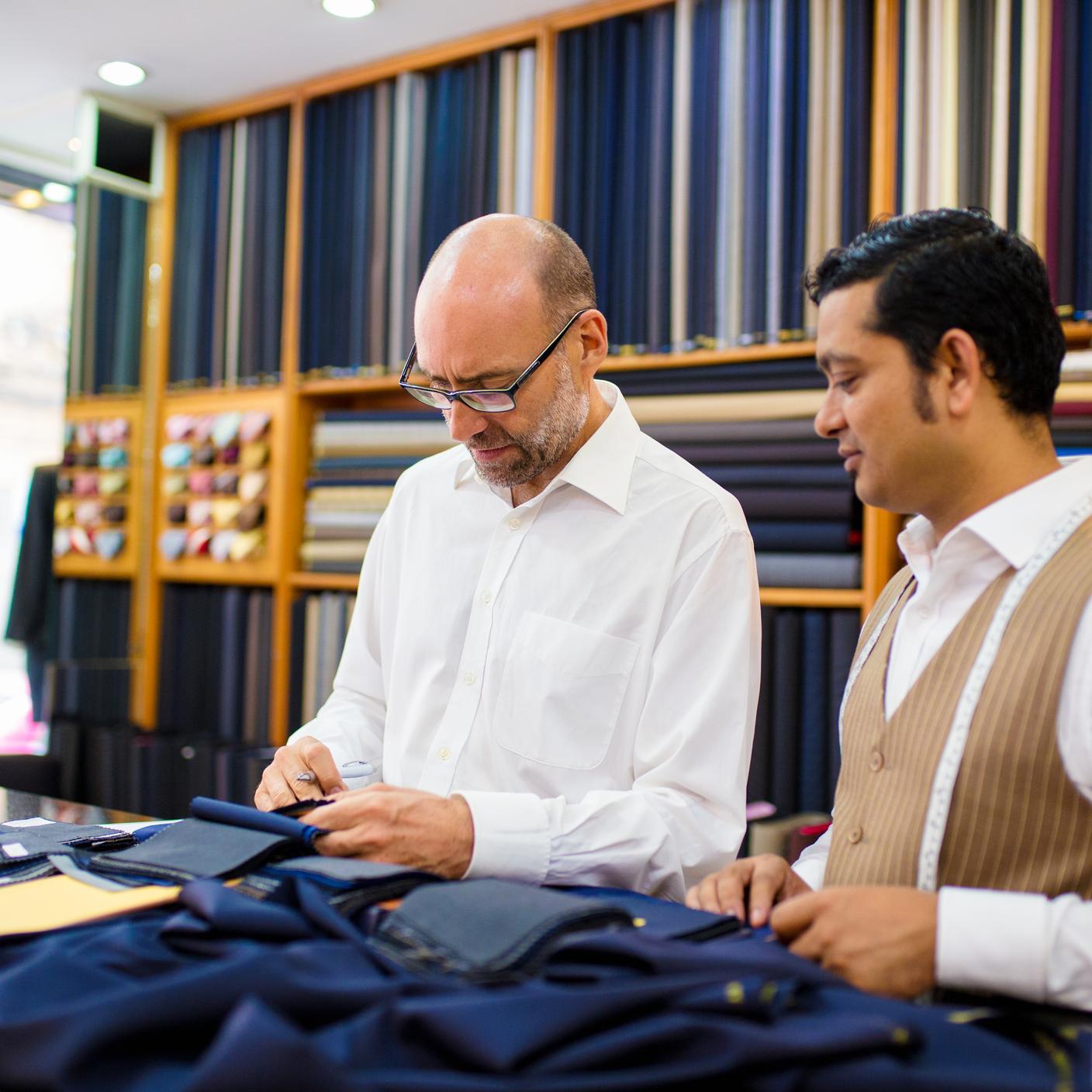 Customer and Tailor looking at fabric swatches in a tailor's shop