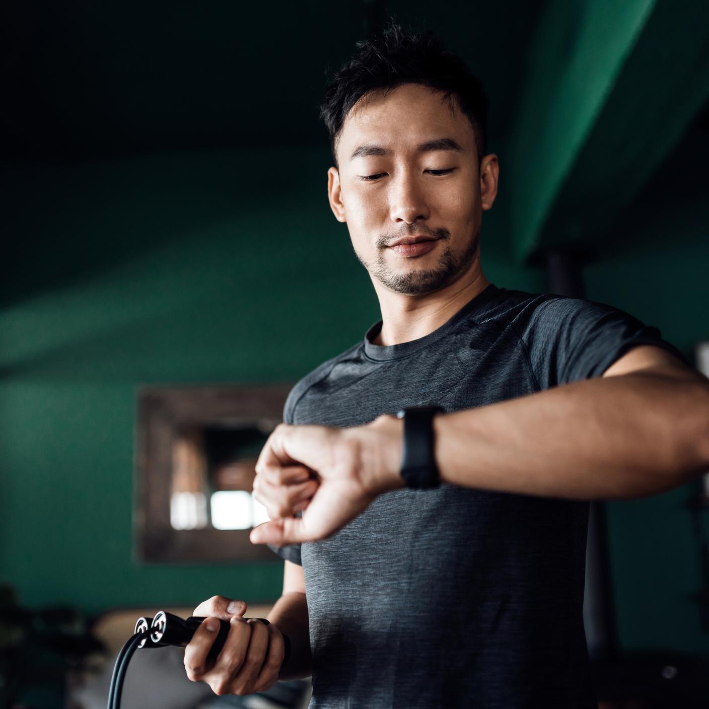 Man exercising at home, using fitness tracker app on smartwatch to monitor training progress