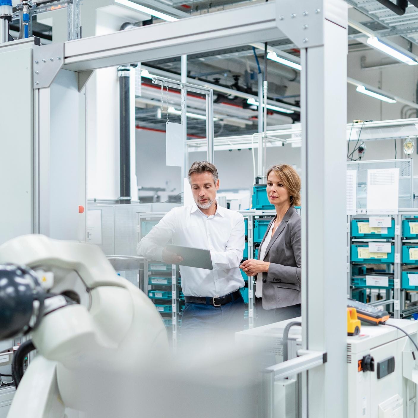 Helping UK manufacturing embrace digitalization - Businesswoman and manwith tablet talking in a modern factory