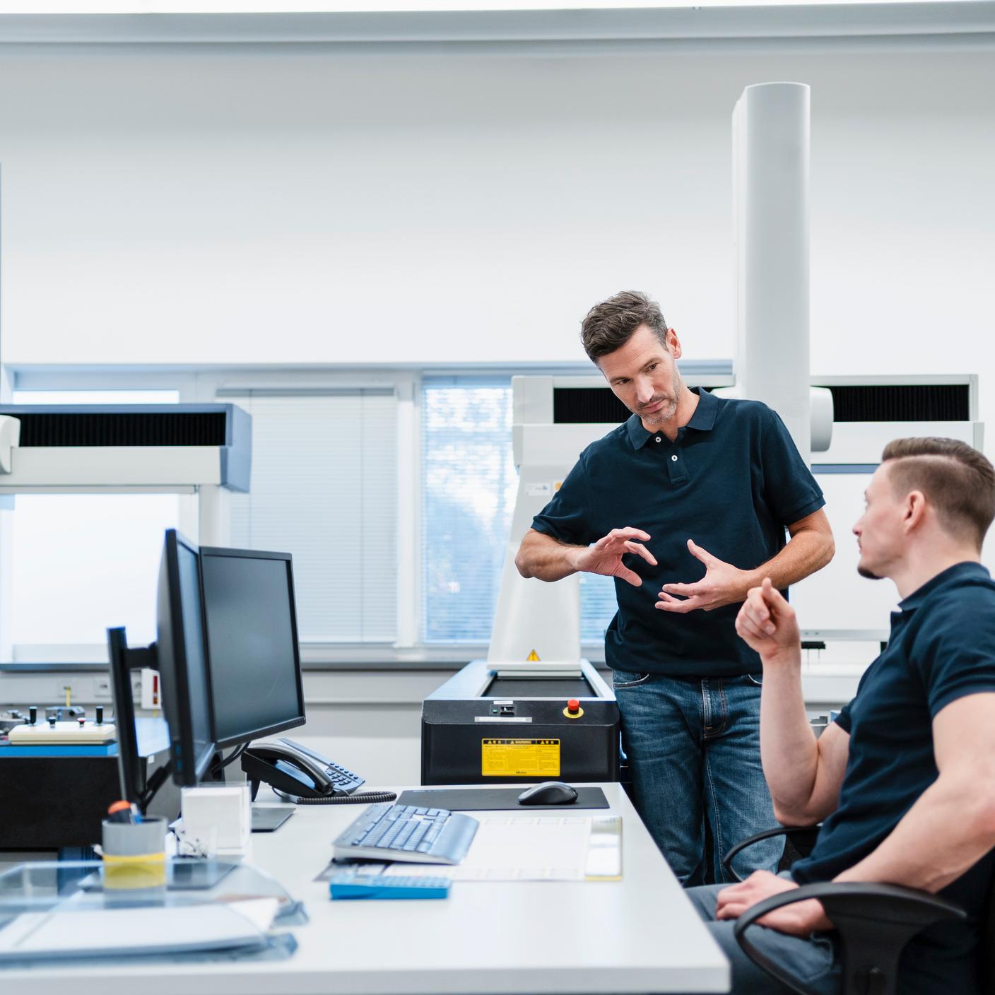 Engineers at desk discussing in industry office