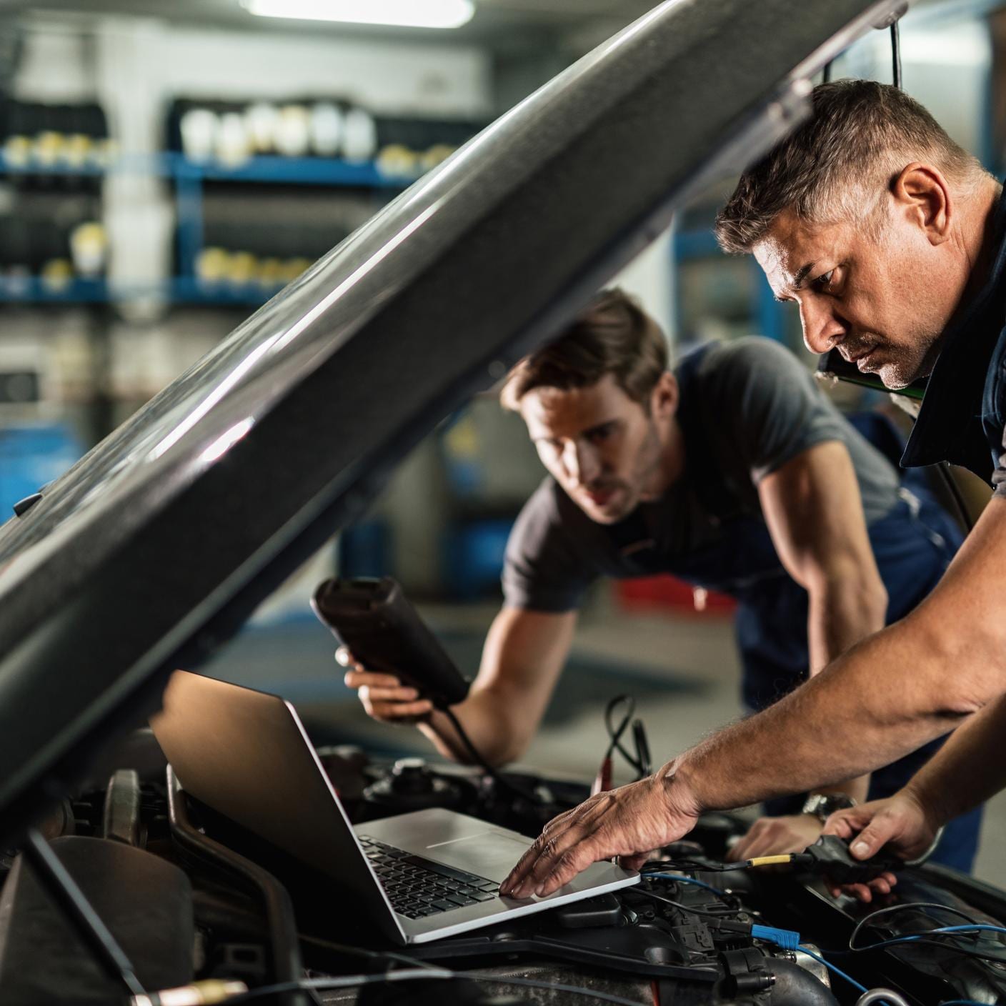 mechanics using laptop under car bonnet