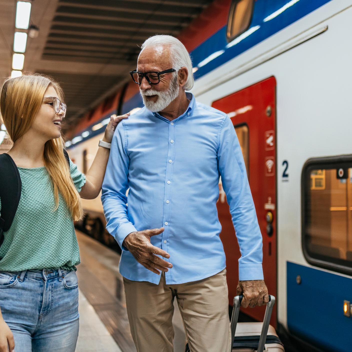 Verkehr & Mobilität – Ein älterer Mann und seine Enkelin am Bahnhof