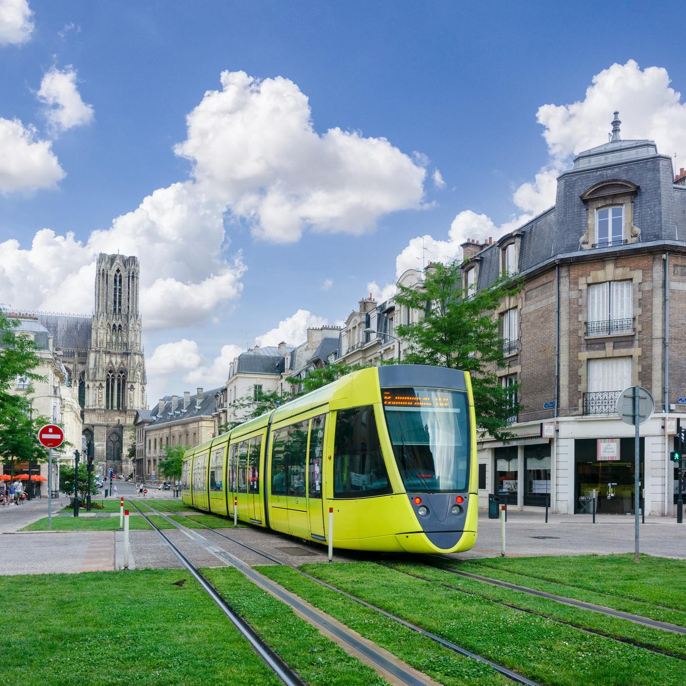 Trams run thru the streets and green city landscape of Reims, France