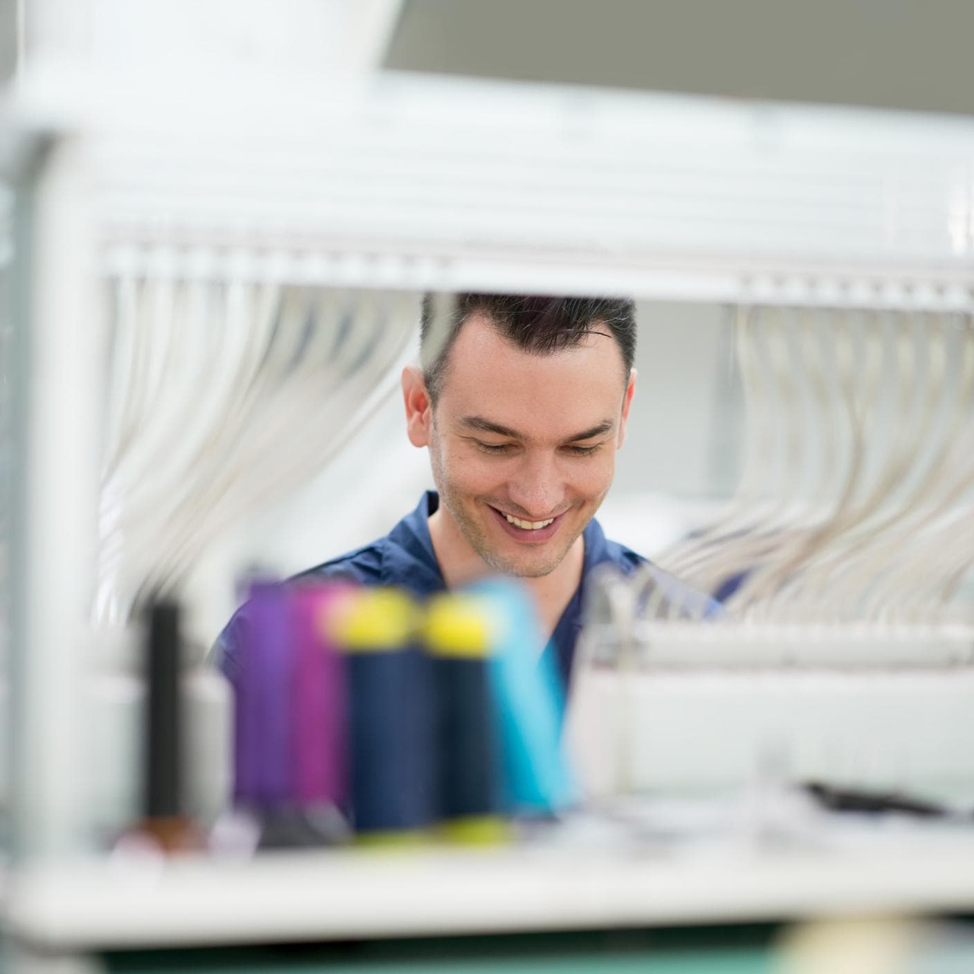 Man operating the embroidery machine at a clothing factory