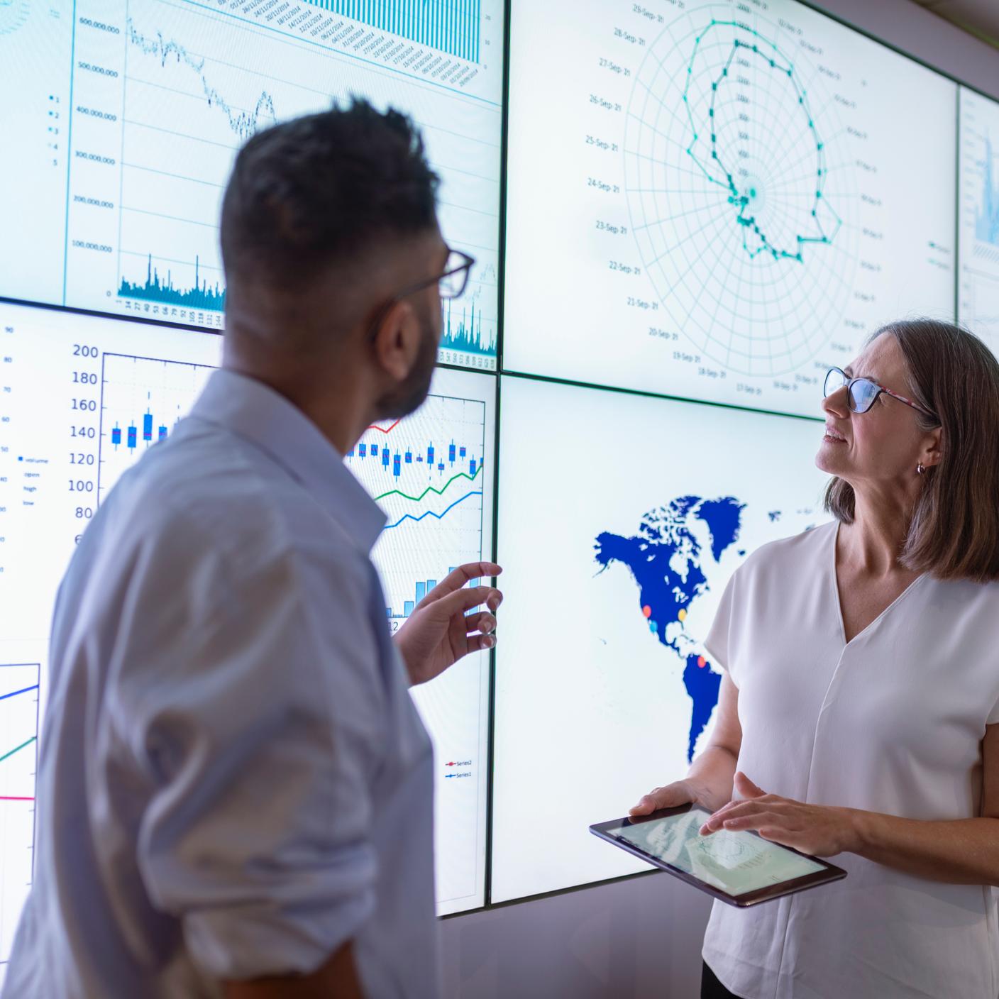 Business people discussing charts on interactive screens