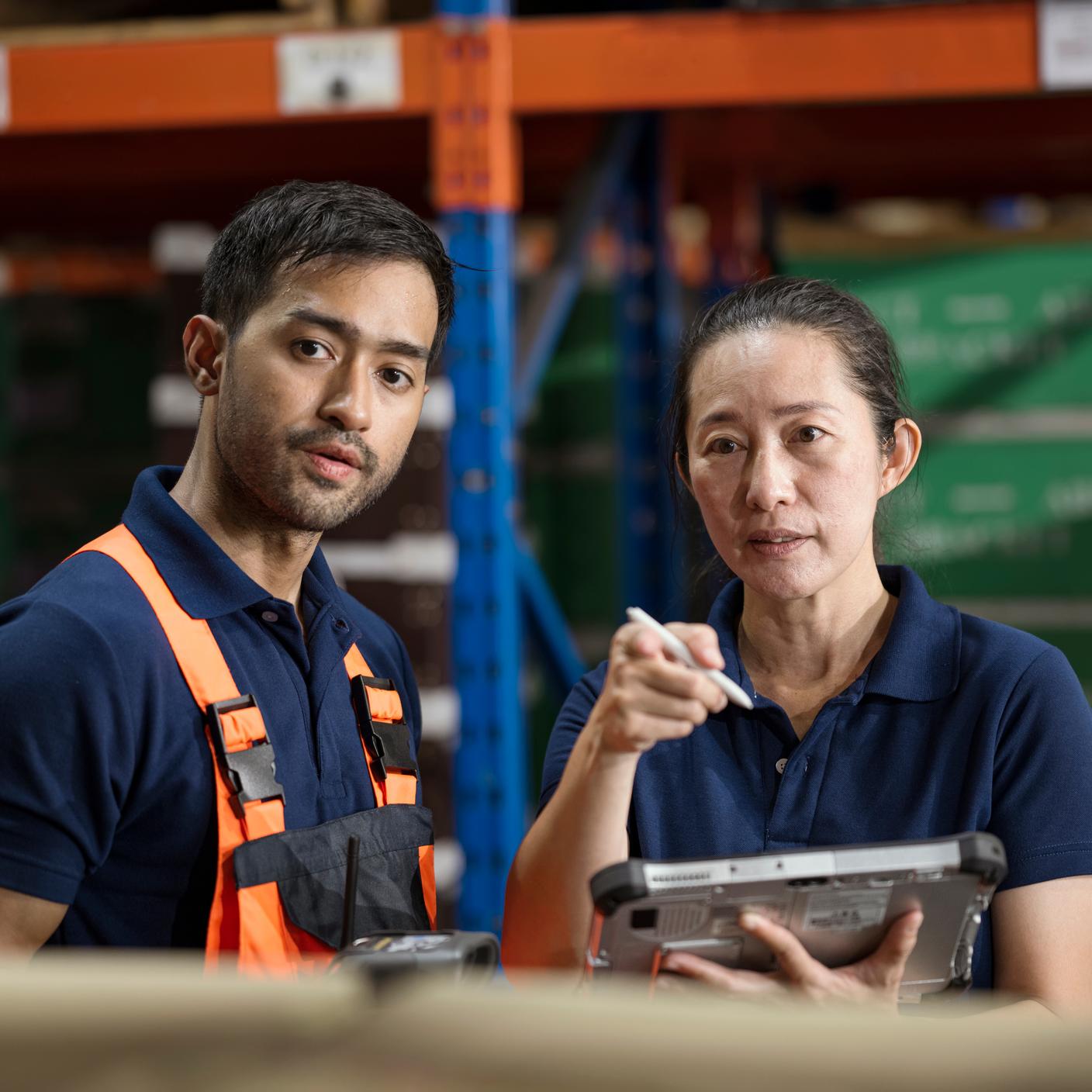 Warehouse manager talking with engineer in warehouse shop floor using tablet 