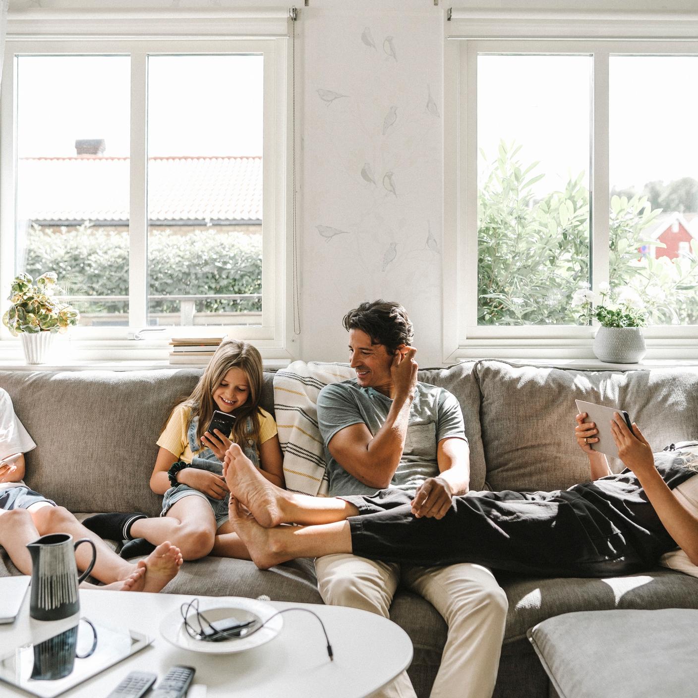 Innovation in ICT - Happy family sitting on sofa in living room