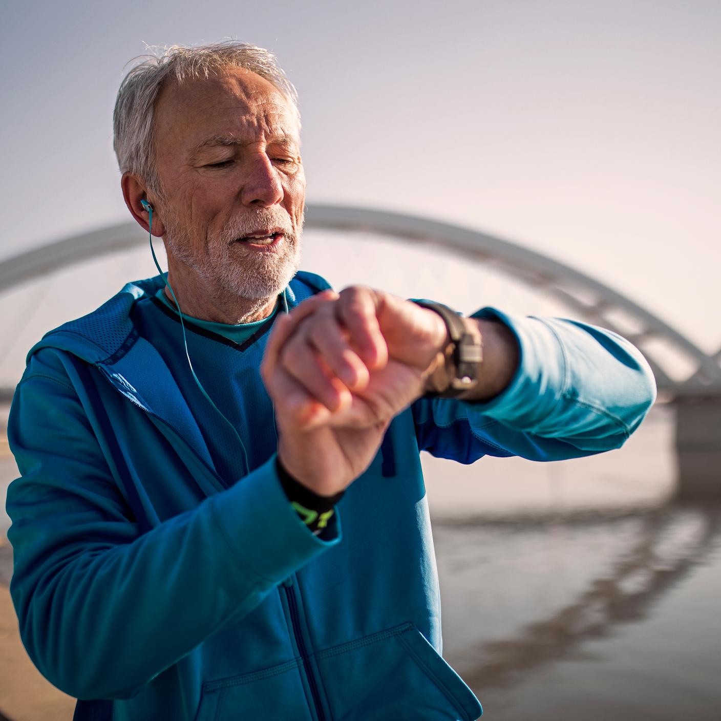 Männlicher Jogger auf Brücke überprüft Smartwatch