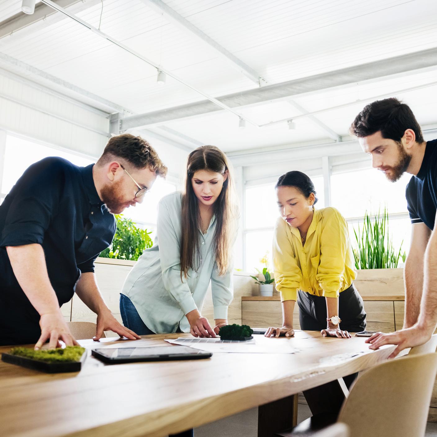 Consultants standing huddled over some documents on a desk